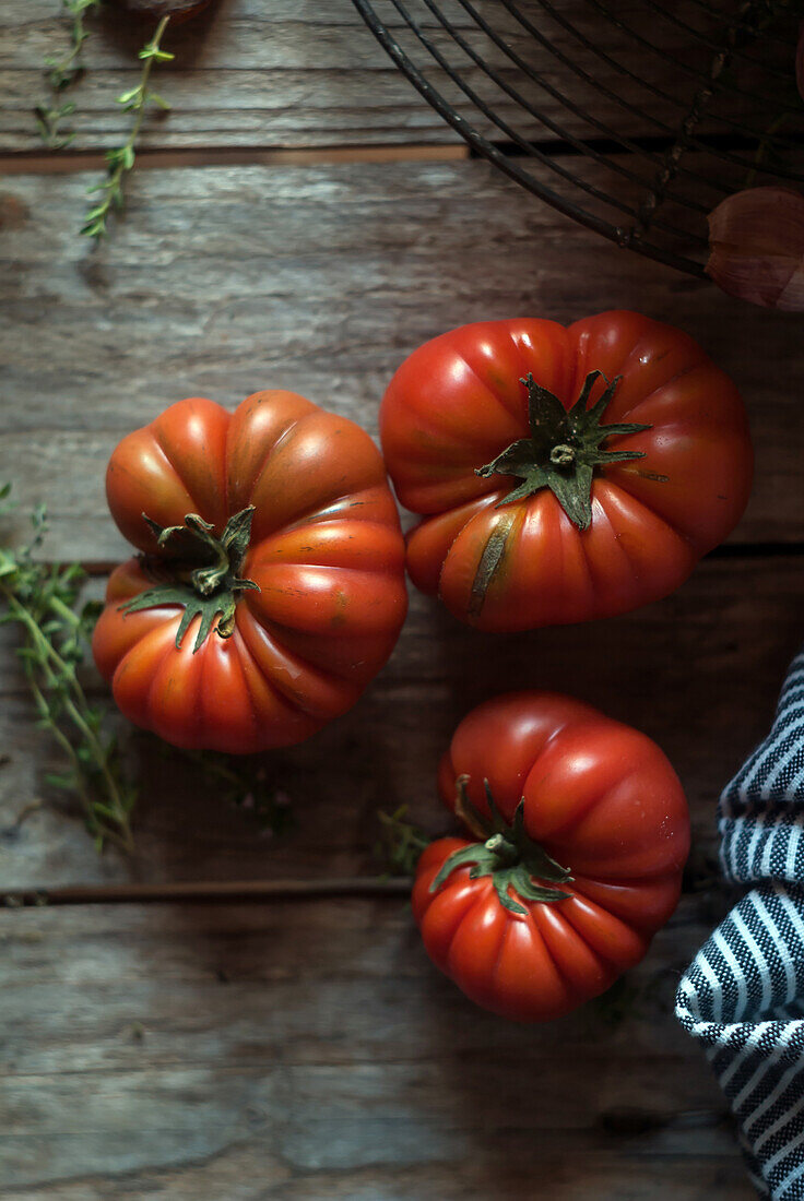 From above of ripe red tomatoes with striped napkin on wooden table