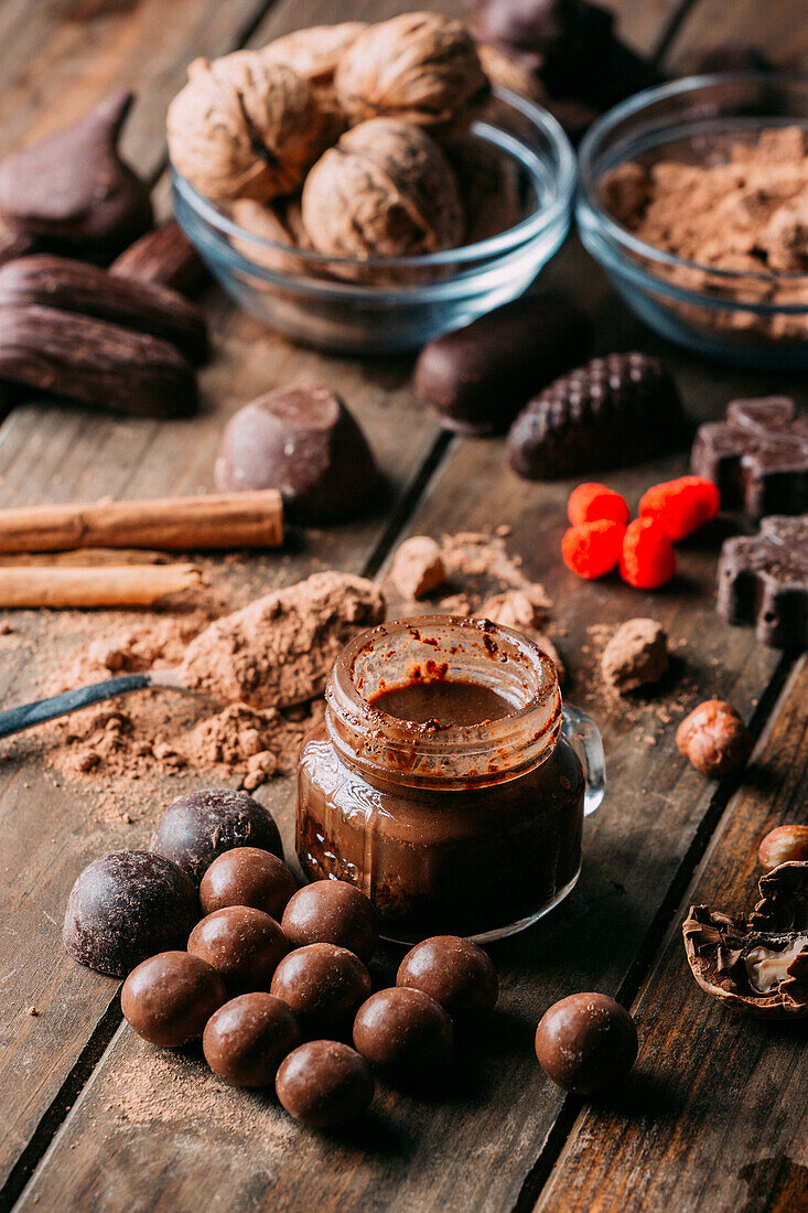 Verschiedene handgemachte Pralinen mit Nüssen auf Holztisch mit Erdnussbutter und Zimtstangen angeordnet