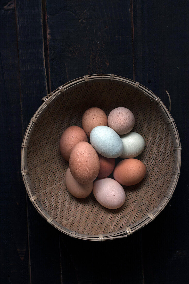 From above shot of wicker basket filled with brown and white eggs on table