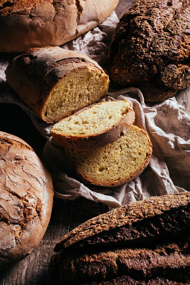 Draufsicht auf frisch gebackene leckere Sauerteigbrote in verschiedenen Formen auf einem Holztisch in einer Bäckerei