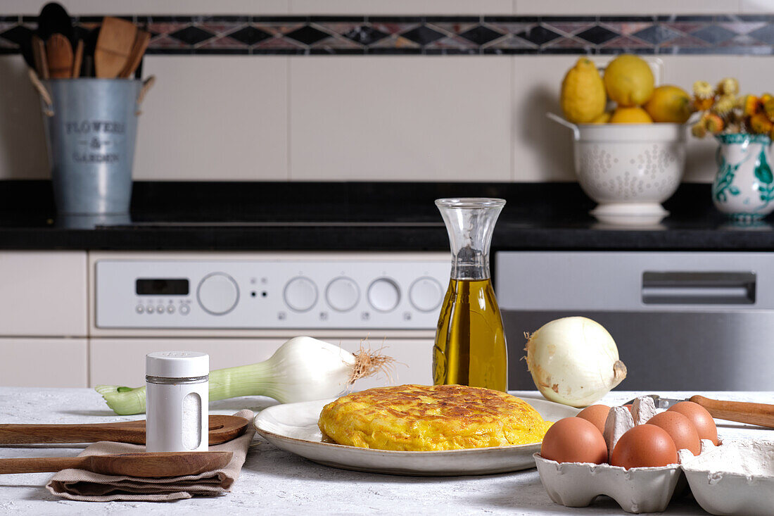 Appetizing traditional Spanish omelette placed on table with eggs and onion in domestic kitchen