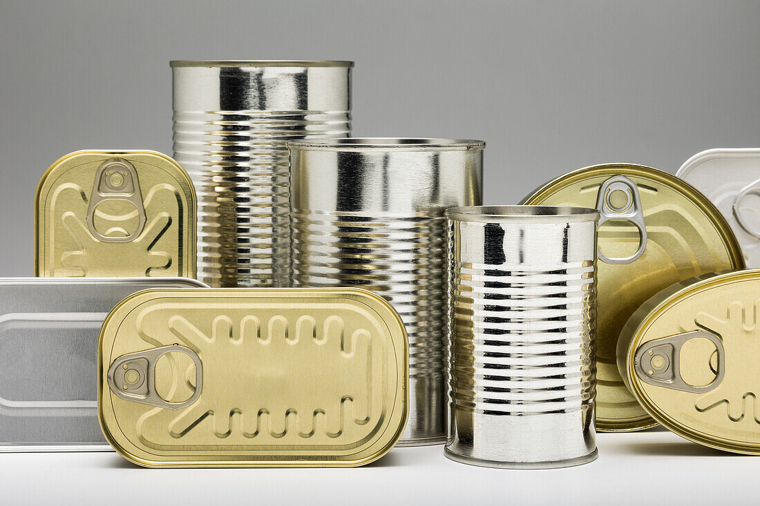 Stacked unopened metal cans on grey background