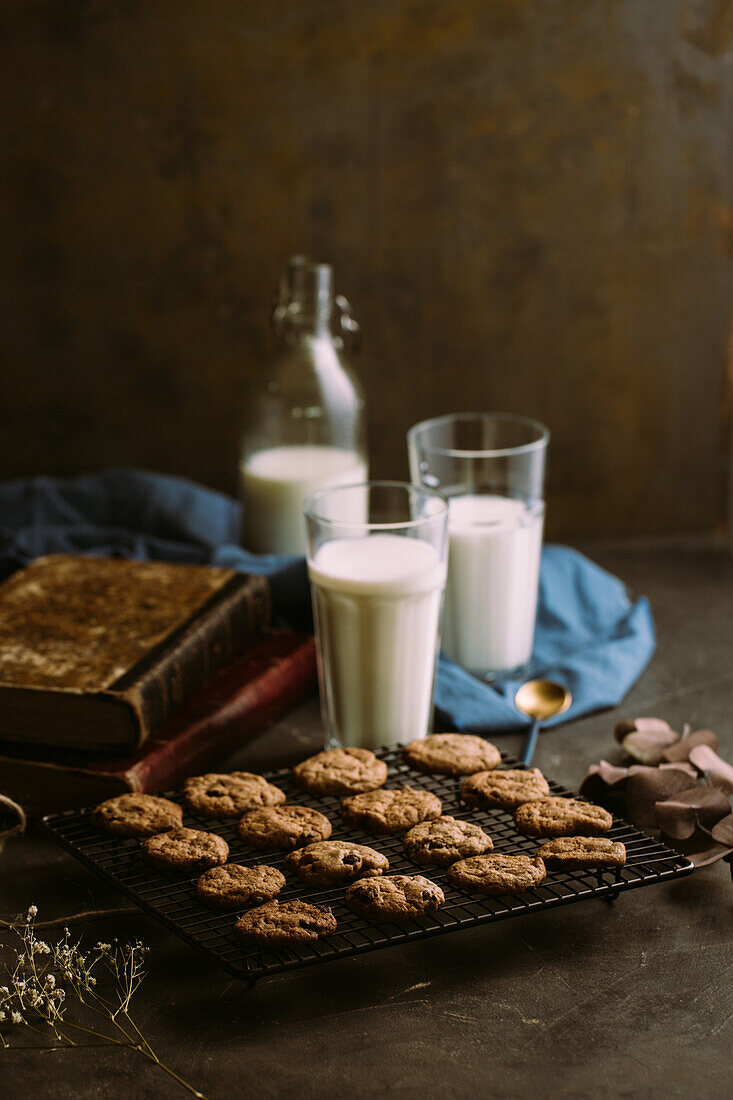 Homemade chocolate chips cookies on cooling rack with a glass of milk