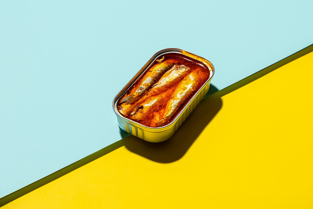 From above composition of canned sardines placed against blue and yellow background