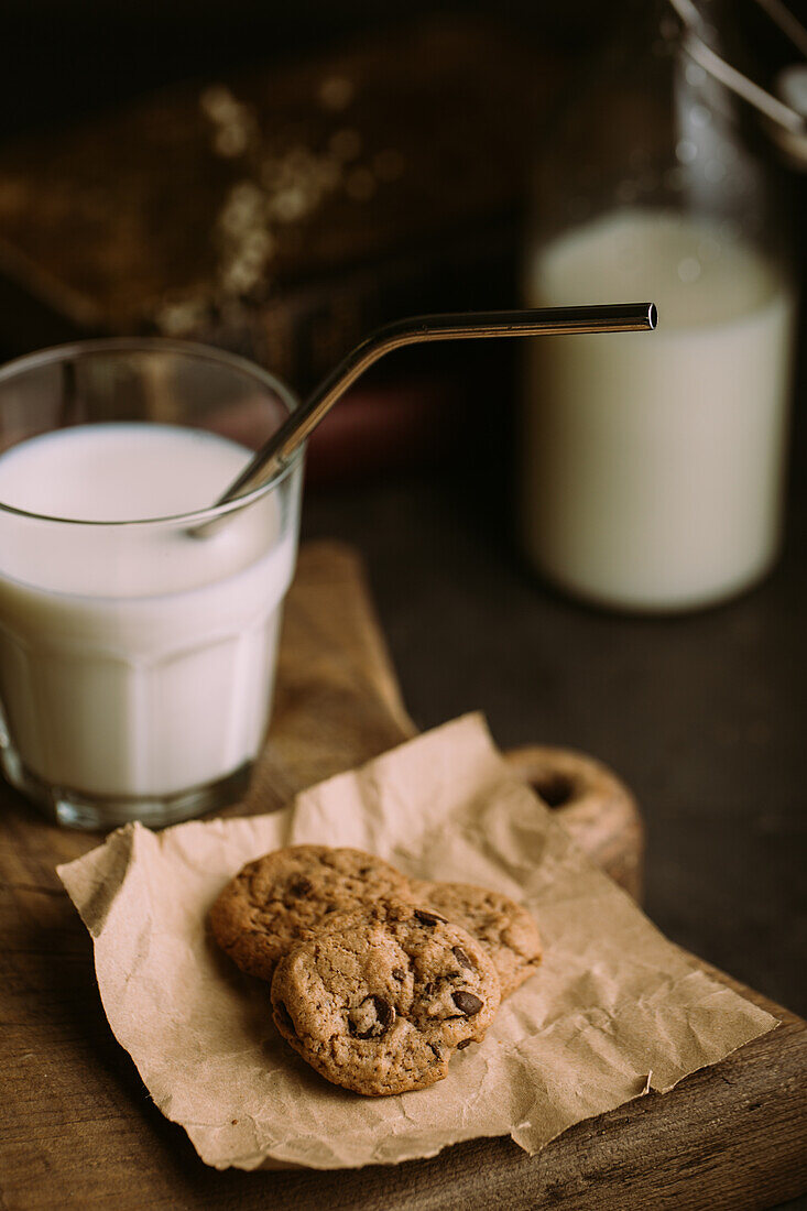 Selbstgebackene Schokoladenkekse mit einem Glas Milch und Strohhalm