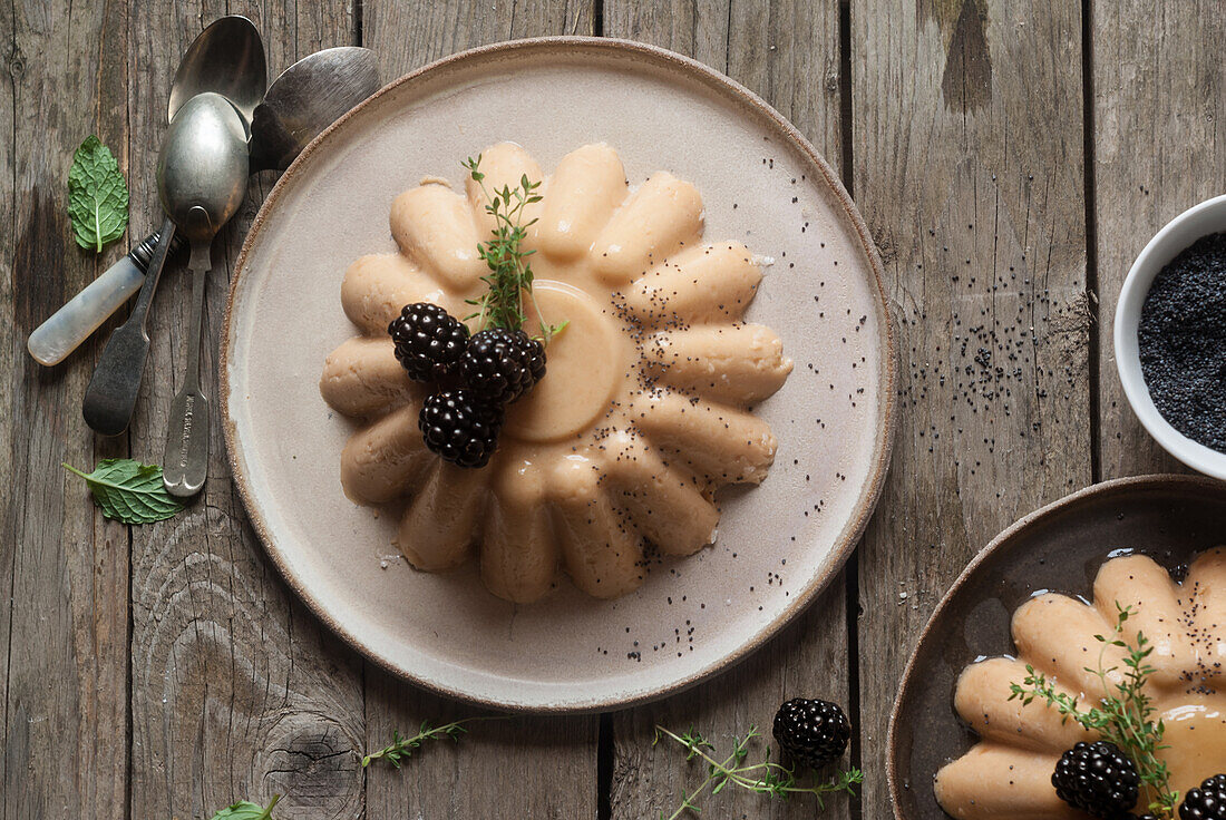 Flat lay of arranged served panna cotta with peach and poppy seeds on table with blackberry