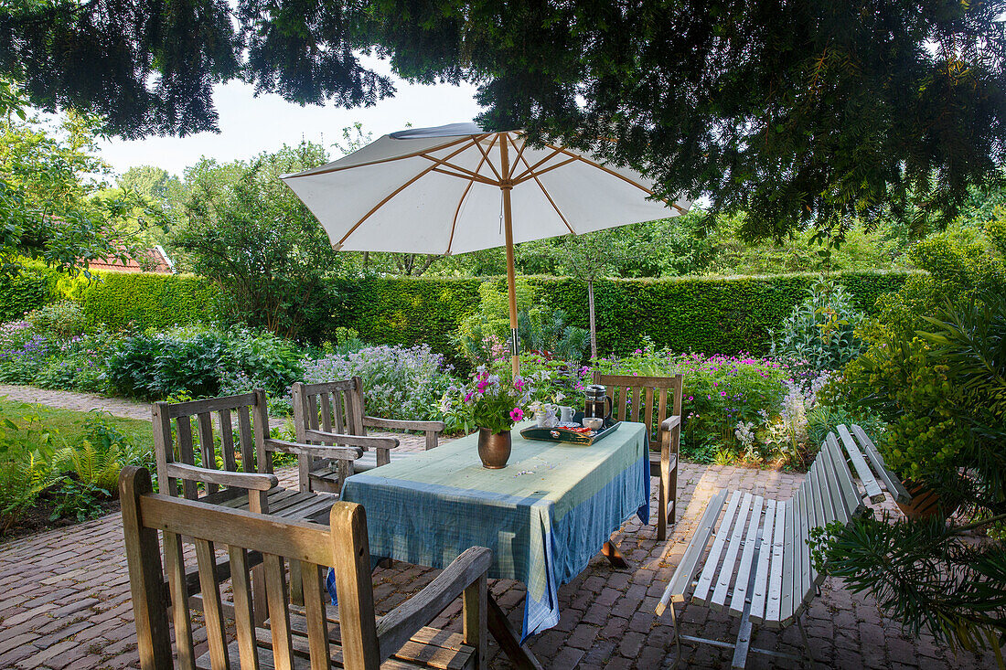 Gartensitzbereich mit Holzmöbeln und Sonnenschirm im Sommer