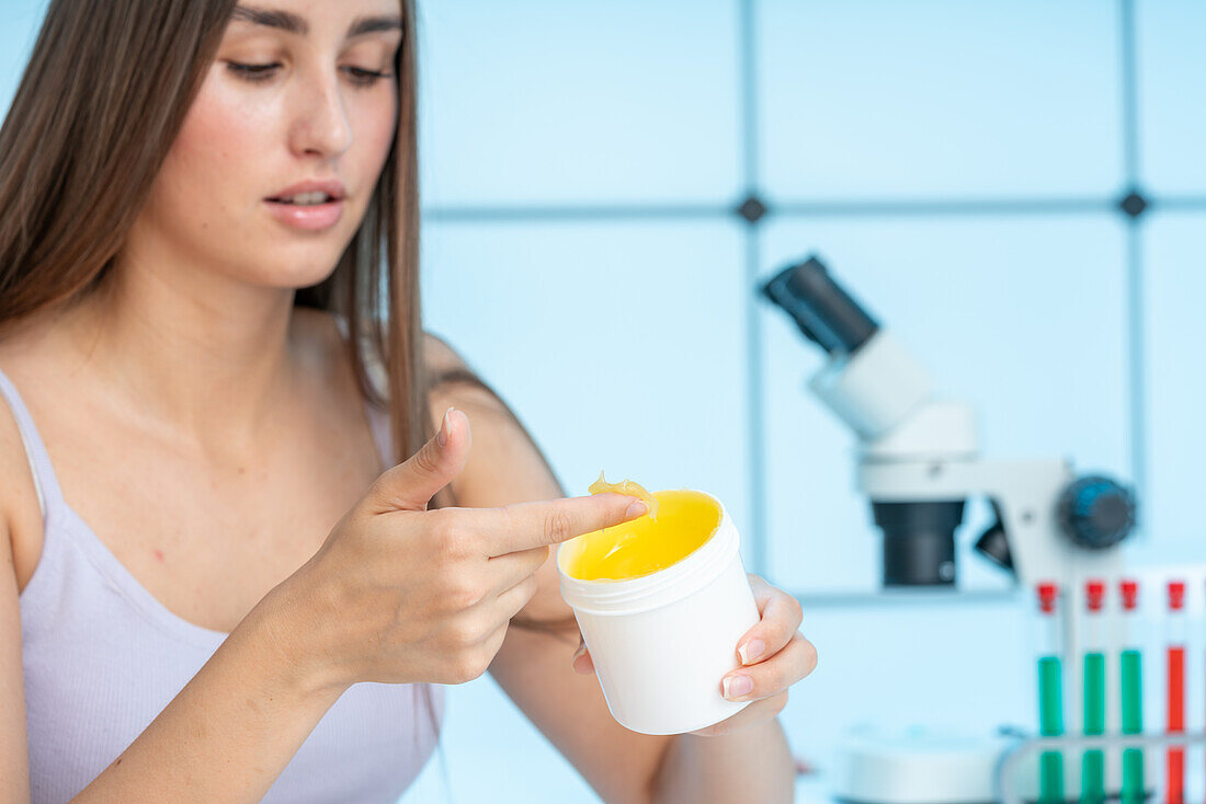 Woman examining ointment from jar