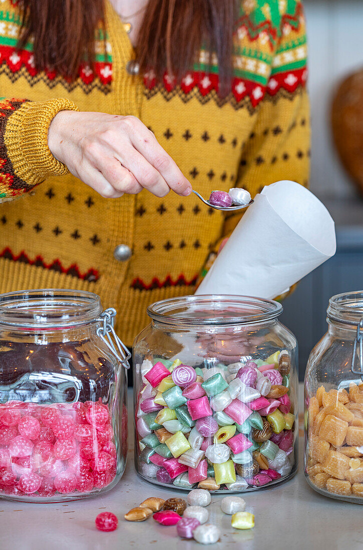 Woman filling sweets from glass containers into paper bags