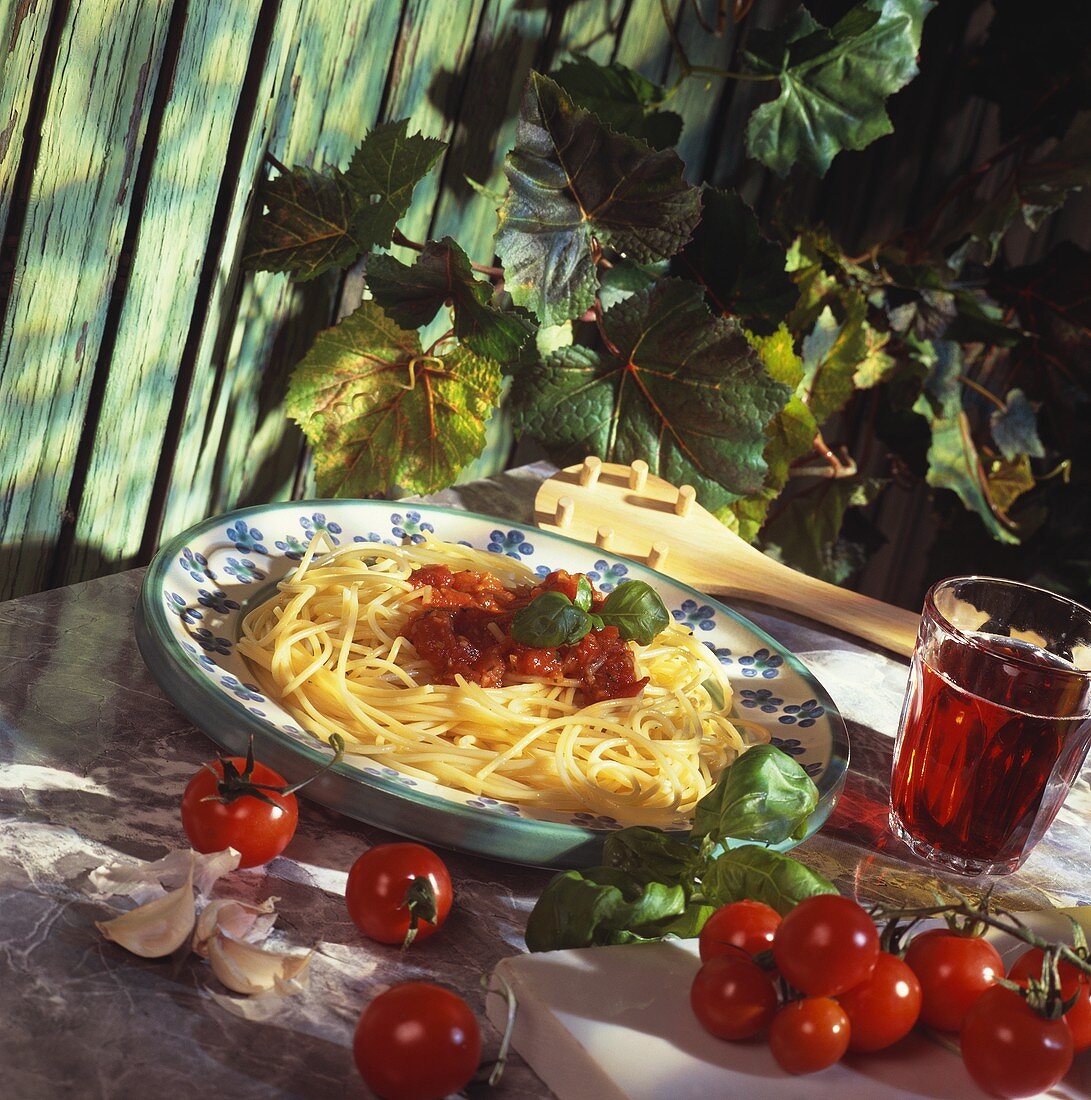 Spaghetti & tomato sauce on plate, decor: ingredients, red wine