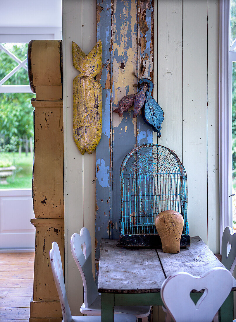 Rustikaler Tisch mit Vogelkäfig und traditionellen Bauernstühlen mit Herz