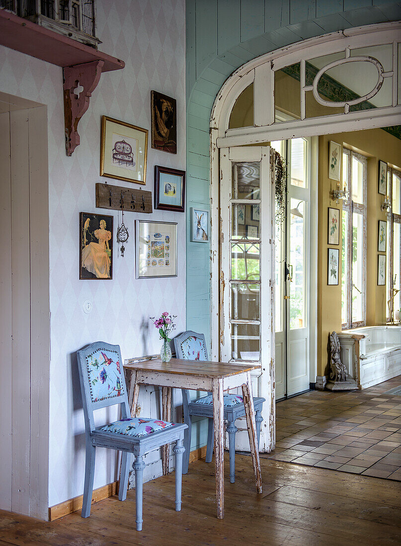 Kleiner Essbereich mit antikem Holztisch und blauen Stühlen vor Wand mit Bildergalerie, Landhausstil