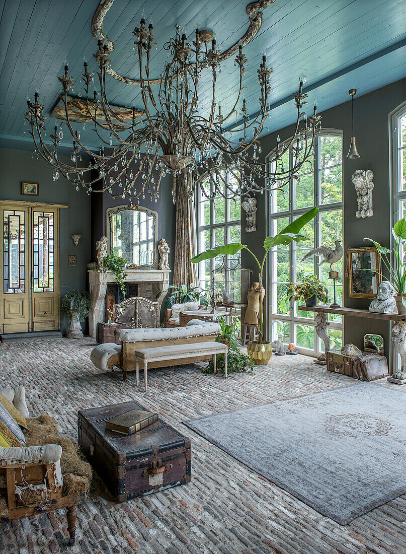 Living room with antique chandelier, stone floor and large mullioned windows