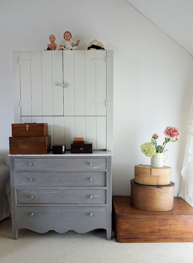 Grey chest of drawers with wooden cupboard and country-style storage boxes