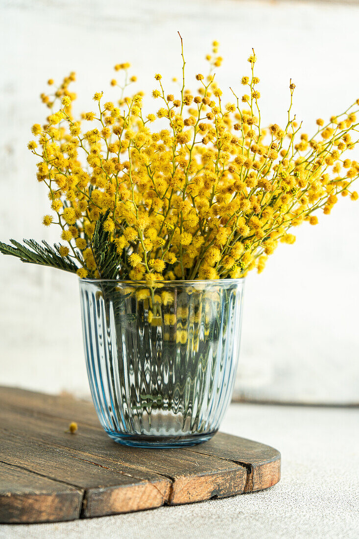 Glass vase with mimosa flowers (Acacia dealbata) on a wooden table