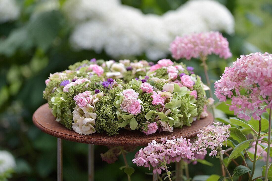 Autumn wreath with hydrangea, sedum and roses on garden table