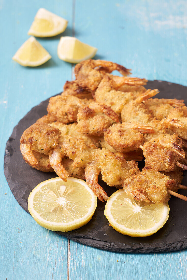 Crispy breaded prawn skewers with lemon