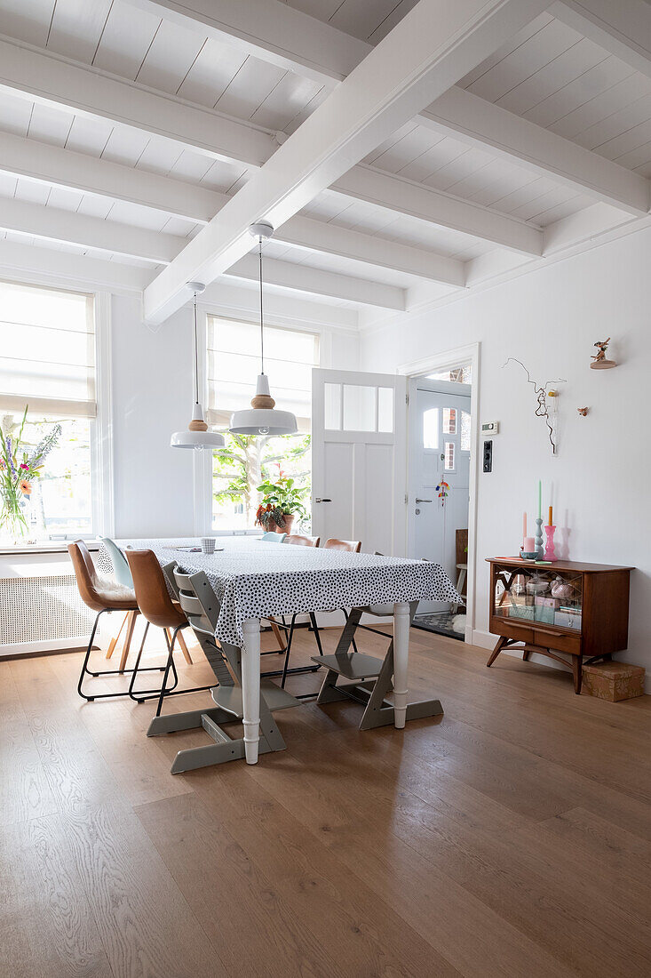 Helles Esszimmer mit Holztisch, Stühlen und weiß gestrichener Holzbalkendecke