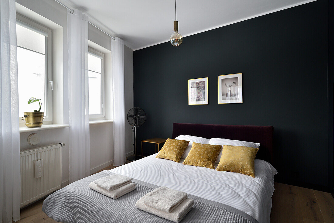 Modern eingerichtetes Schlafzimmer mit dunkler Wand und goldfarbenen Akzenten
