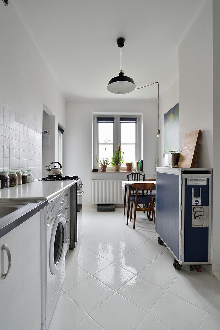 Narrow kitchen with washing machine and dining area by the window