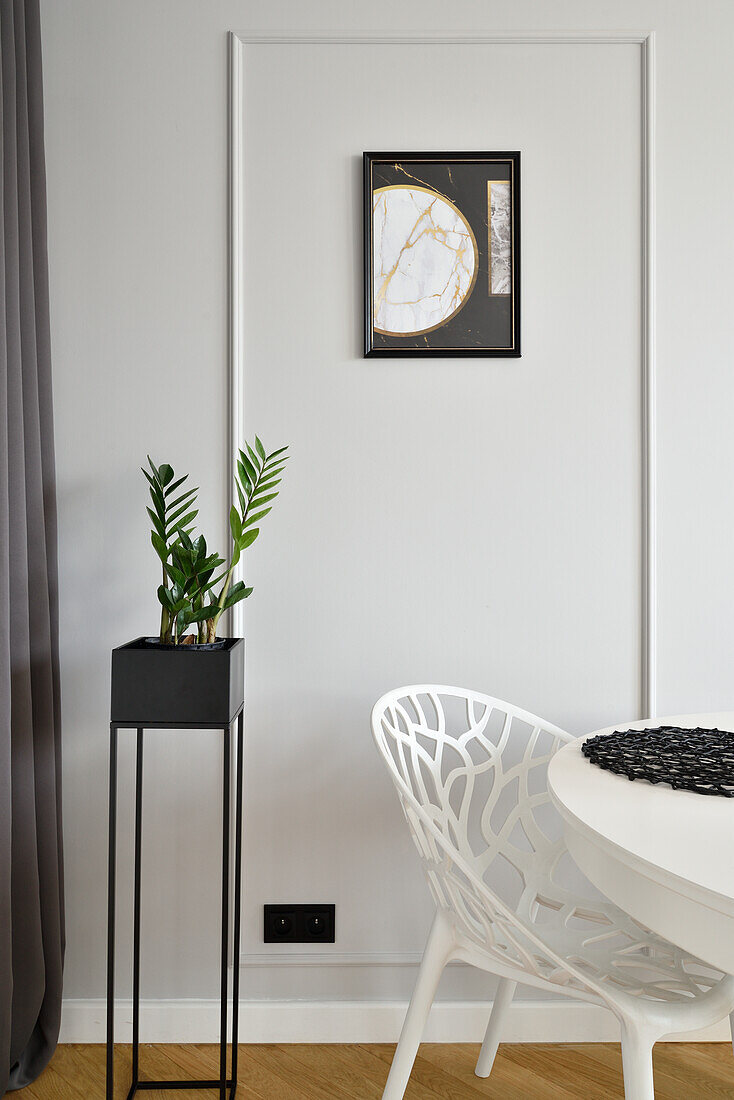 Modern corner with plant, picture on the wall and white chair