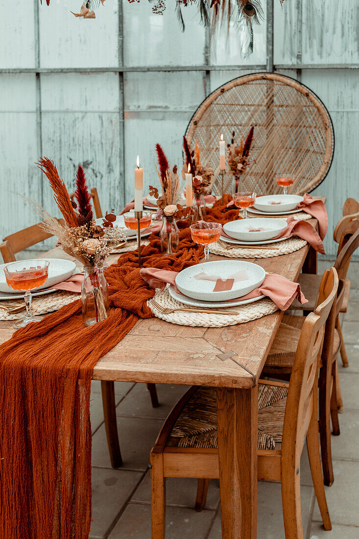 Gedeckter Esstisch mit Herbstdekoration, Trockenblumen und Kerzen