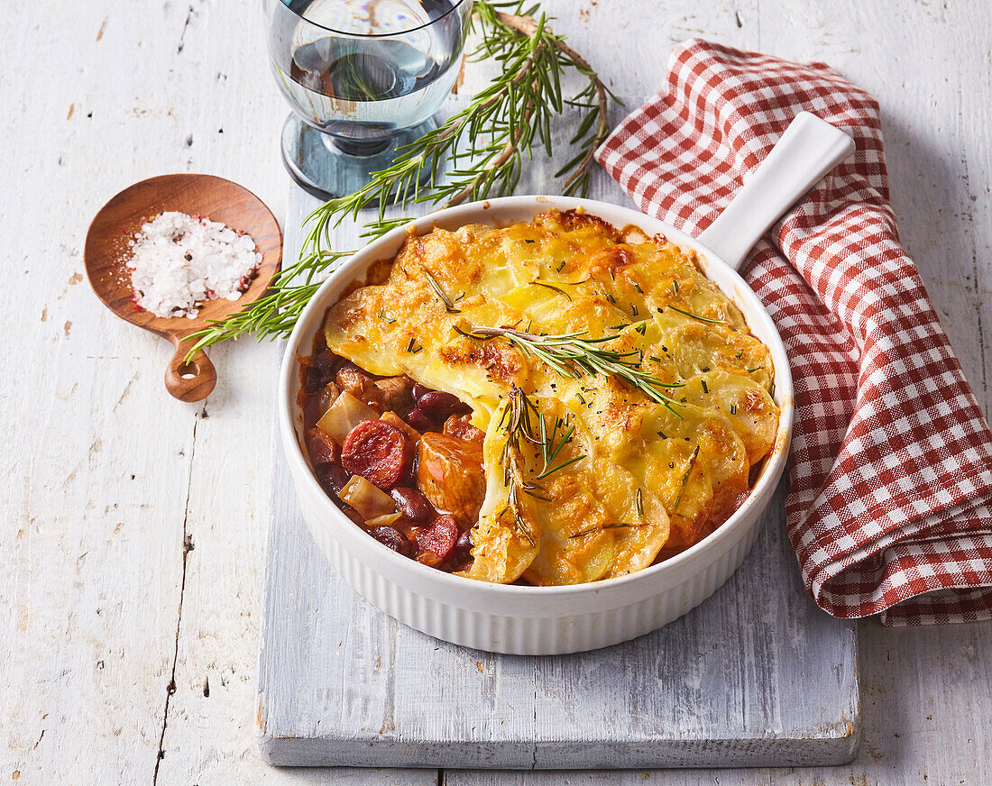 Potato casserole with beef, sausage and cheese, garnished with rosemary