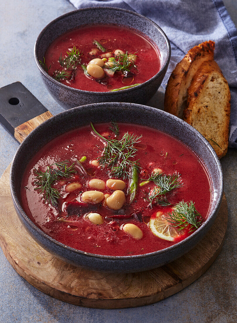 Beetroot soup with beans and dill, served with lemon and bread