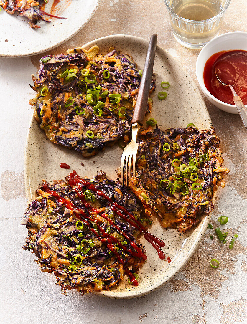 Rotkohl-Puffer mit Karotten und Frühlingszwiebeln, serviert mit Sriracha-Sauce