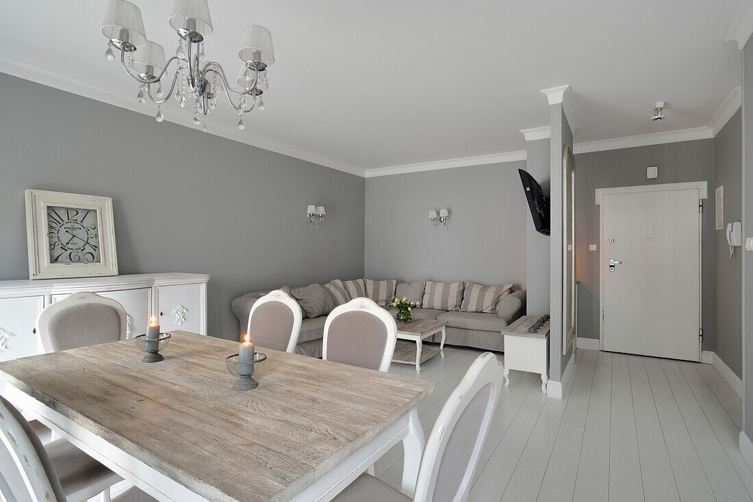 Dining area with chandelier and living room with corner sofa in grey tones