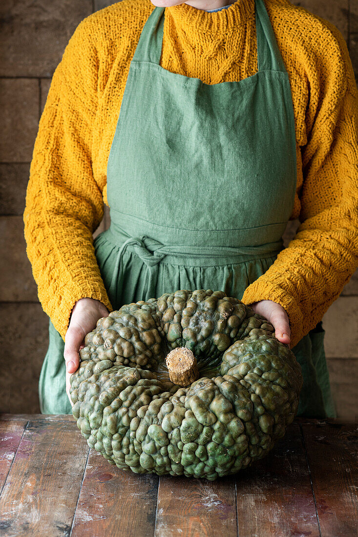 Woman holding large green warty pumpkin