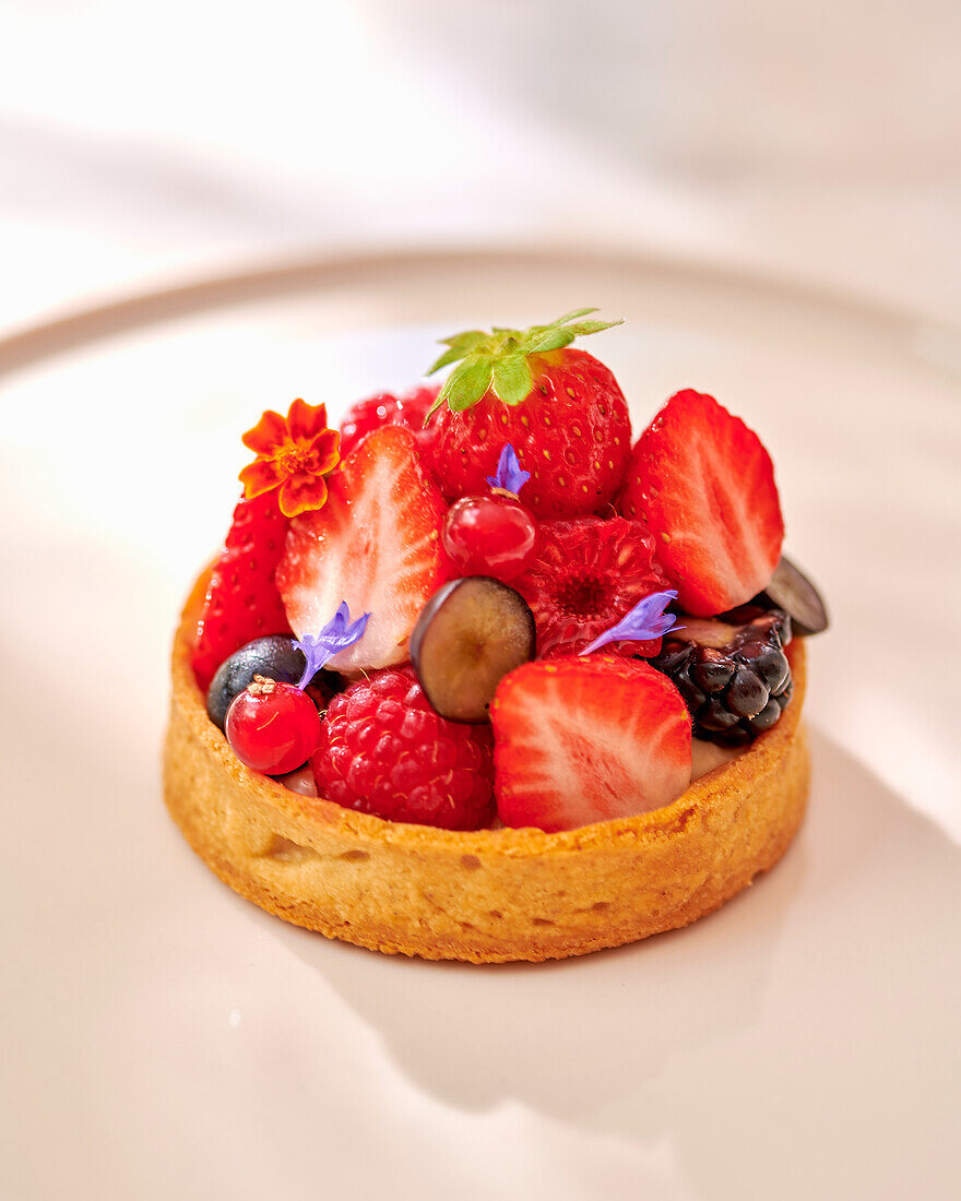 Summer berry tartelette with edible flowers