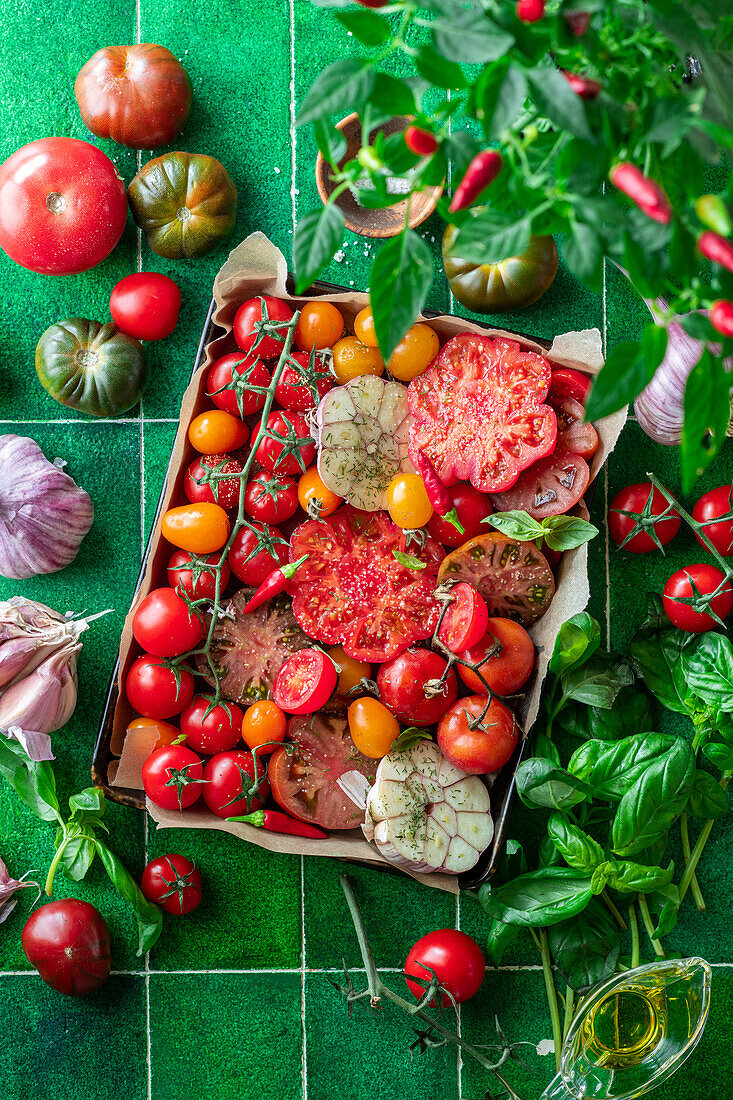 Different types of tomatoes with garlic and basil on a baking tray
