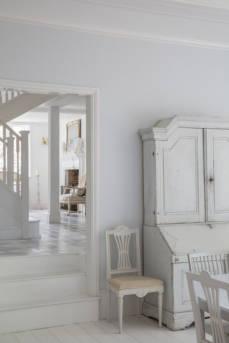 White-painted hallway with antique cabinet and wooden chair