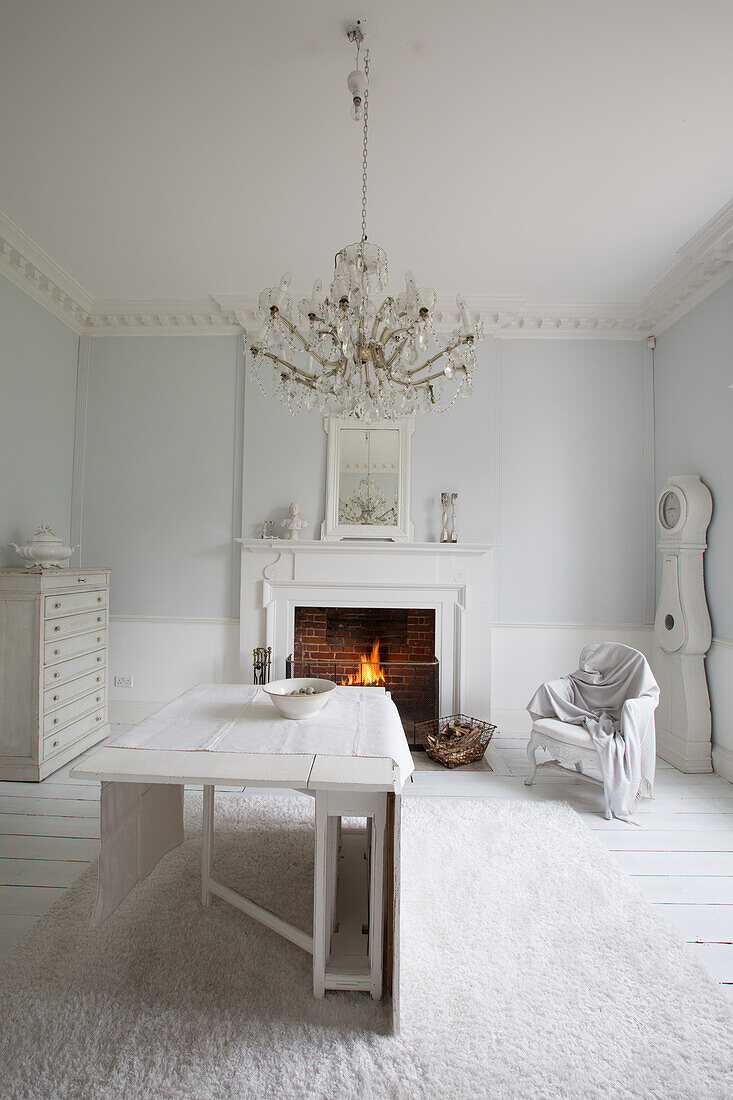 Bright living room with fireplace, chandelier and white wooden table