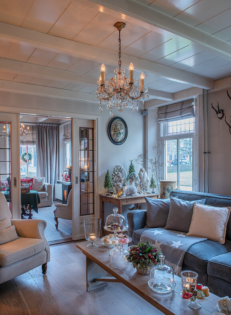 Living room decorated for Christmas with vintage chandelier, wooden beamed ceiling and candles