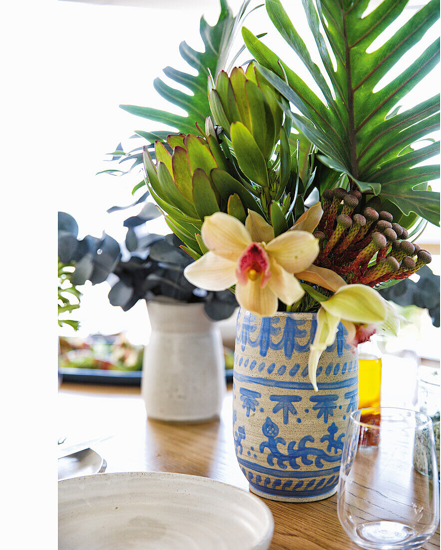 Orchidee und exotische Pflanzen in Vase als Tischdeko
