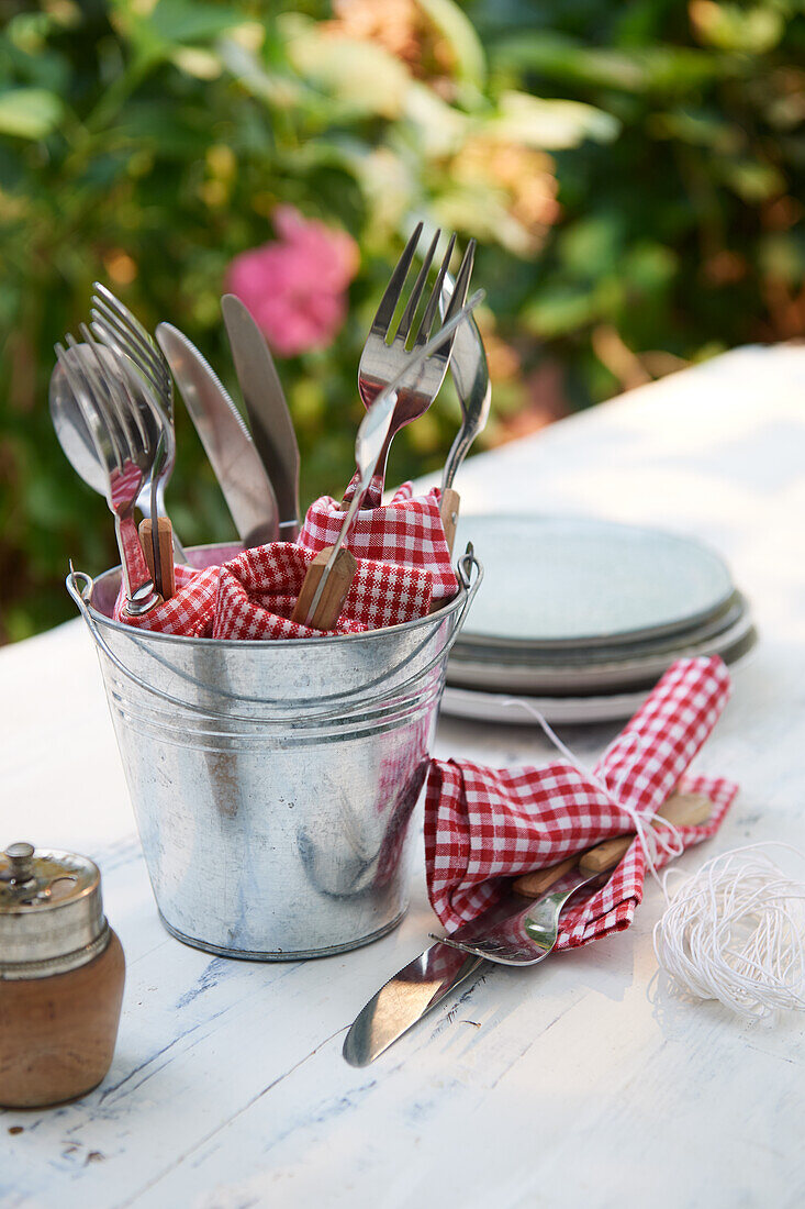 Cutlery and chequered napkins in a zinc bucket