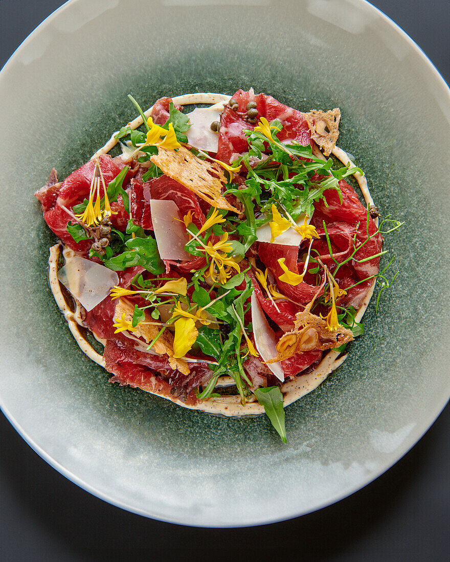 Carpaccio vom geräucherten Rind mit Wildkräutern, Blüten und Parmesanchips