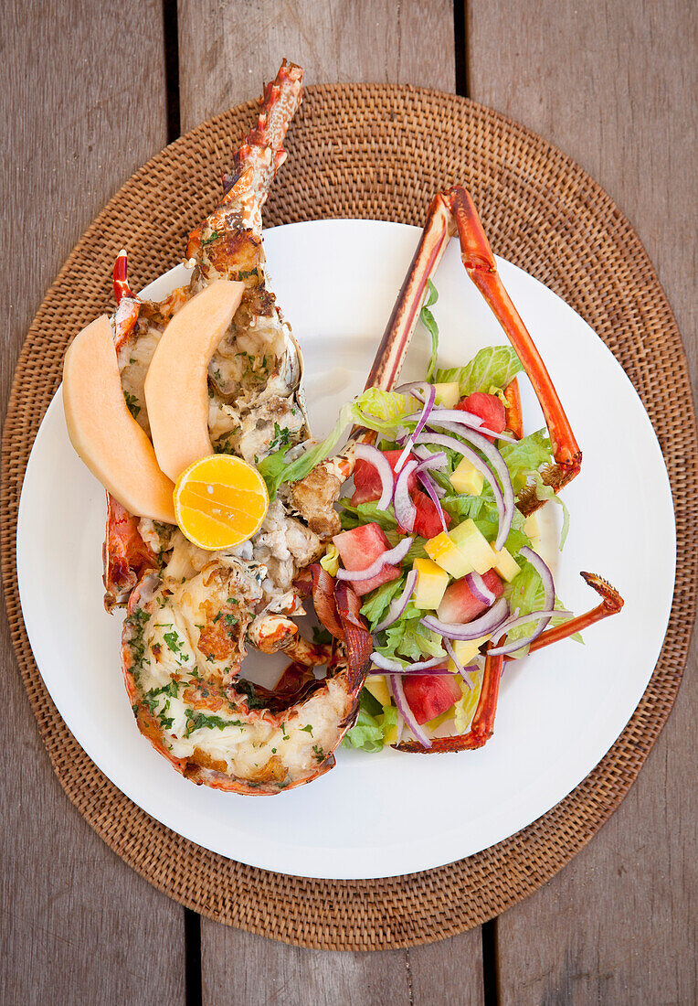 Grilled lobster with fruit salad on a white plate