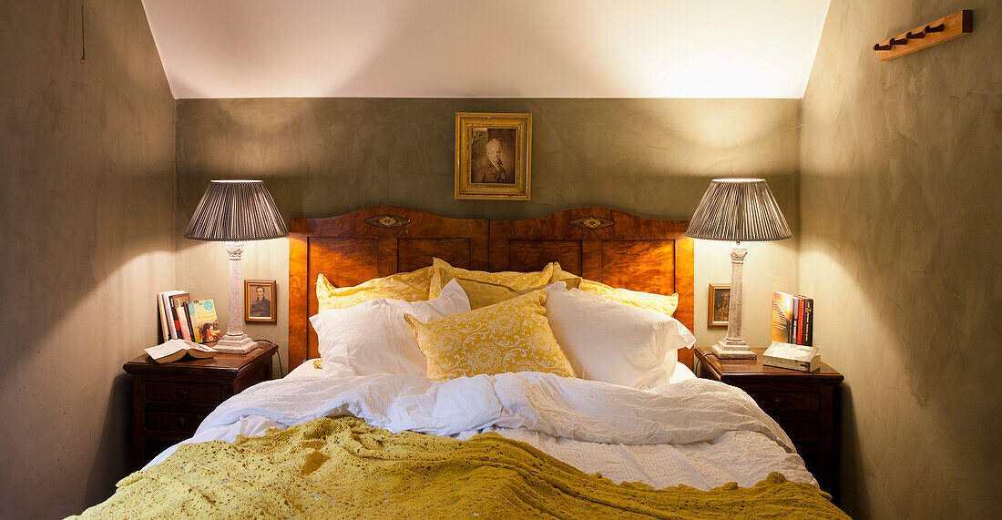 Antique double bed with mustard yellow bedspread and bedside lamps in the bedroom