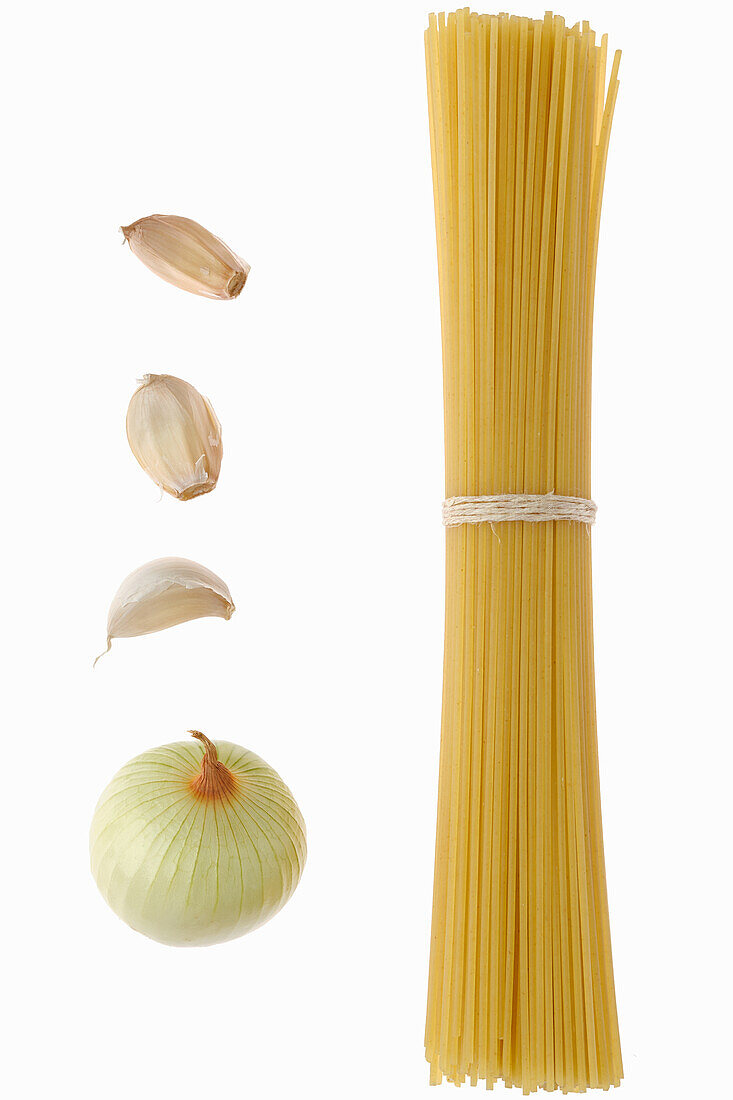 Bundle of spaghetti with garlic cloves and onion