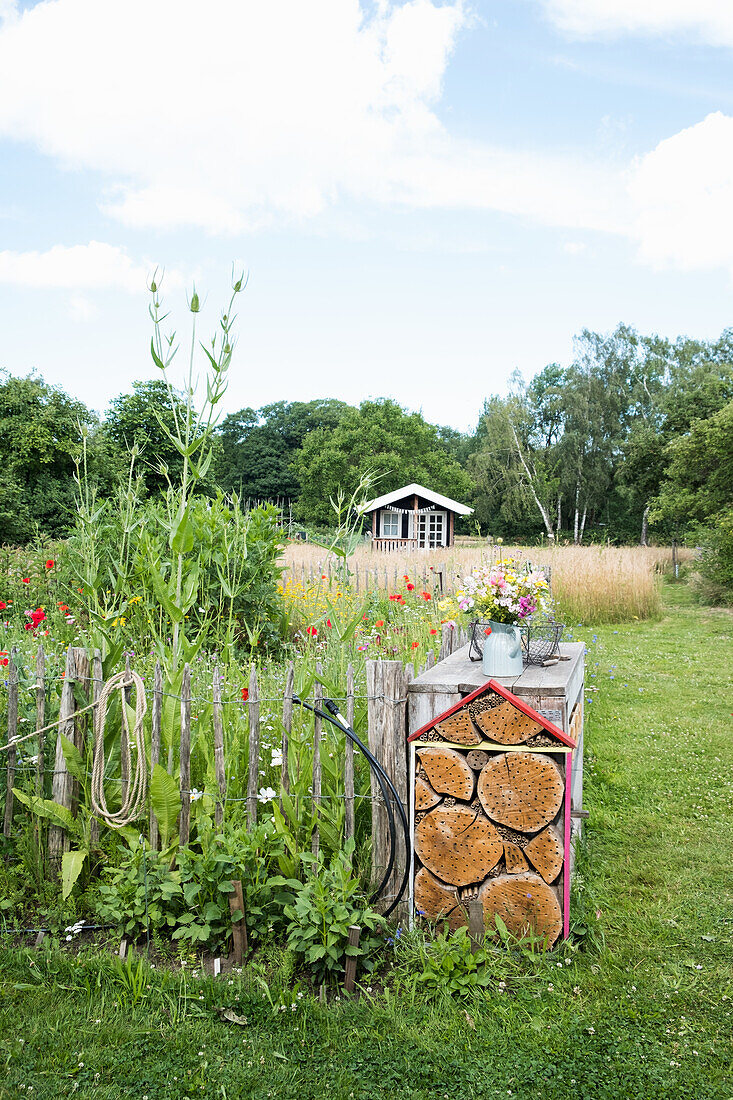 Garten mit Blumenbeet, Insektenhotel und Sommerwiese im Hintergrund