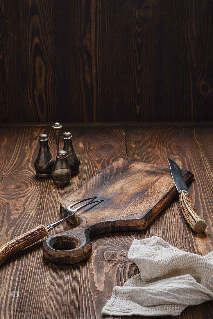 Still life with chopping board and cutlery on a rustic wooden table