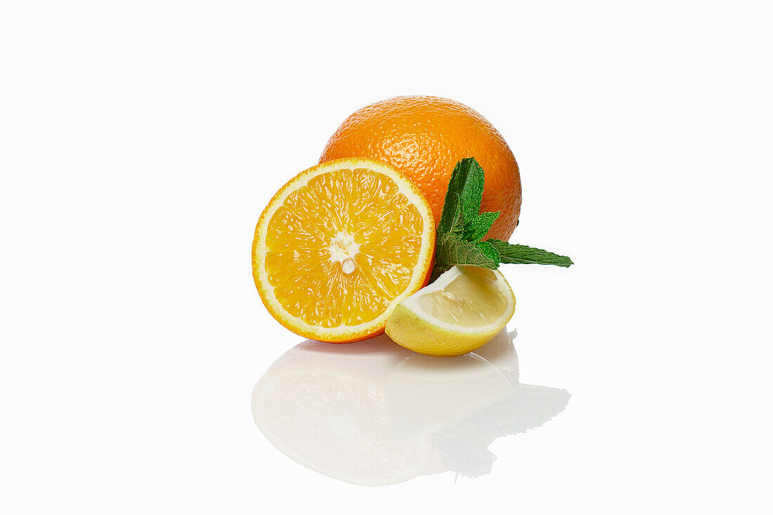 Whole and halved orange with lemon wedge and mint