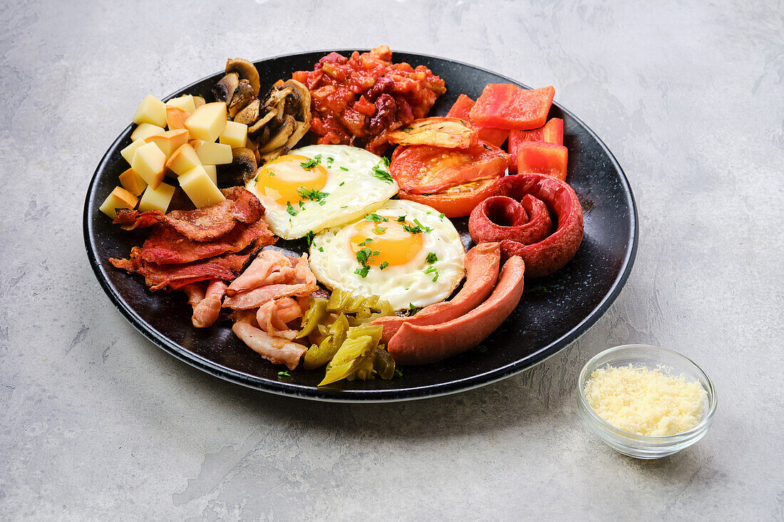 Englisches Frühstück mit Spiegeleiern, Würstchen und gebratenem Gemüse