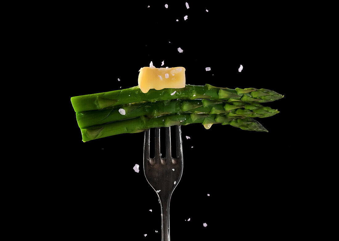 Green asparagus with melting butter and salt on a fork
