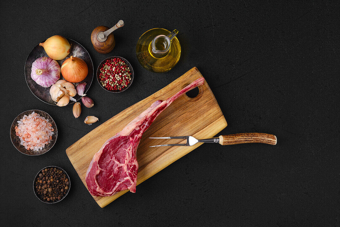 Raw cowboy steak with spices and herbs