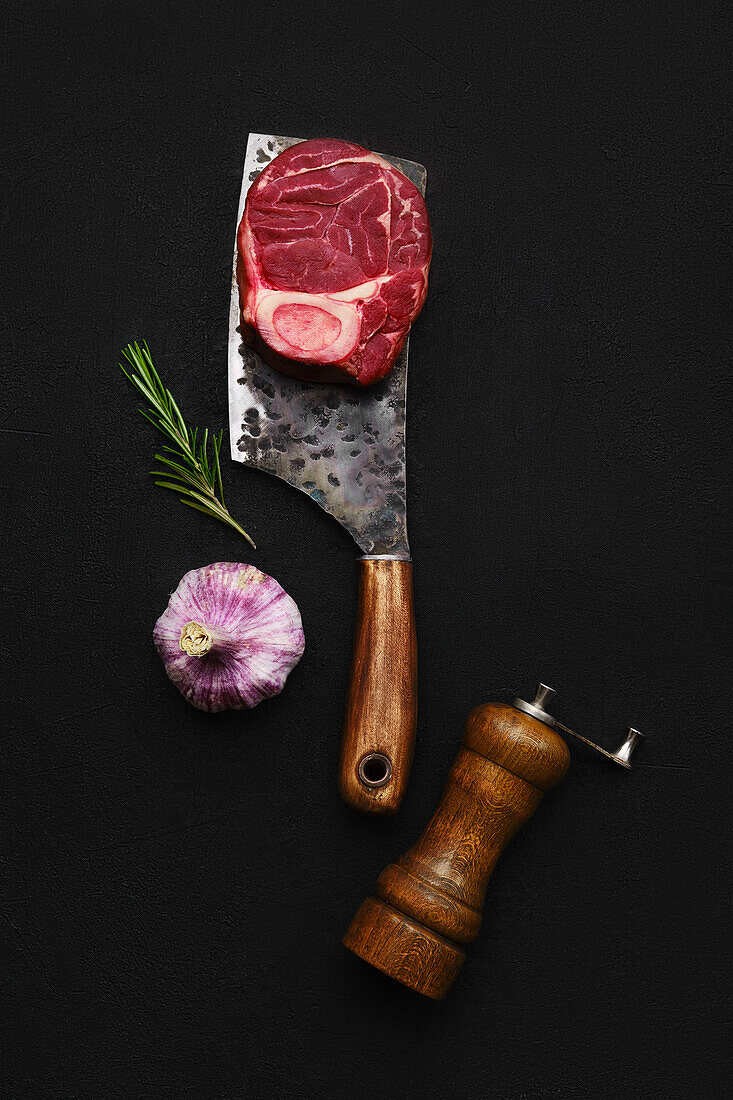 Raw ossobuco on a butcher's cleaver with rosemary and garlic