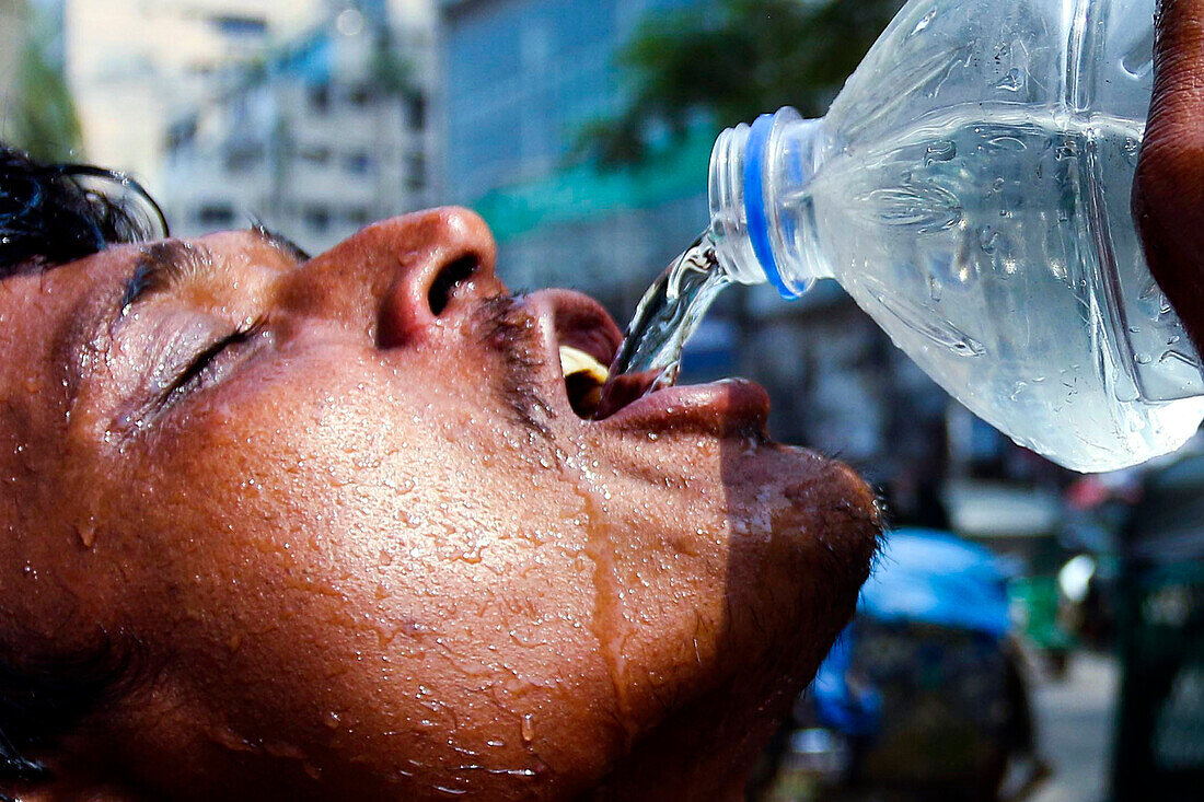 Man drinking water in heatwave, Bangladesh